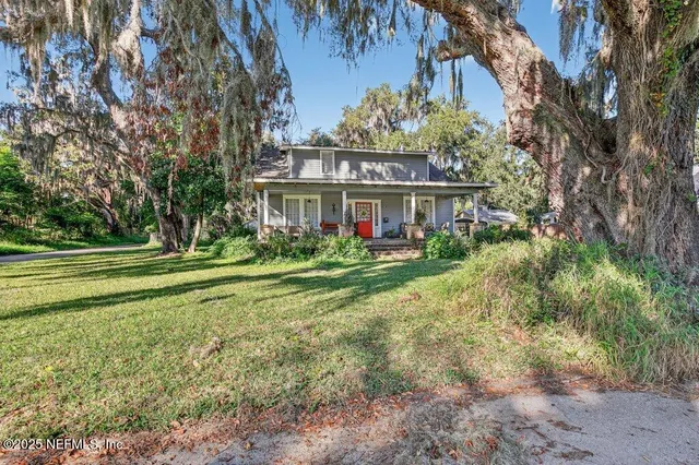 a view of a house with a big yard and large trees