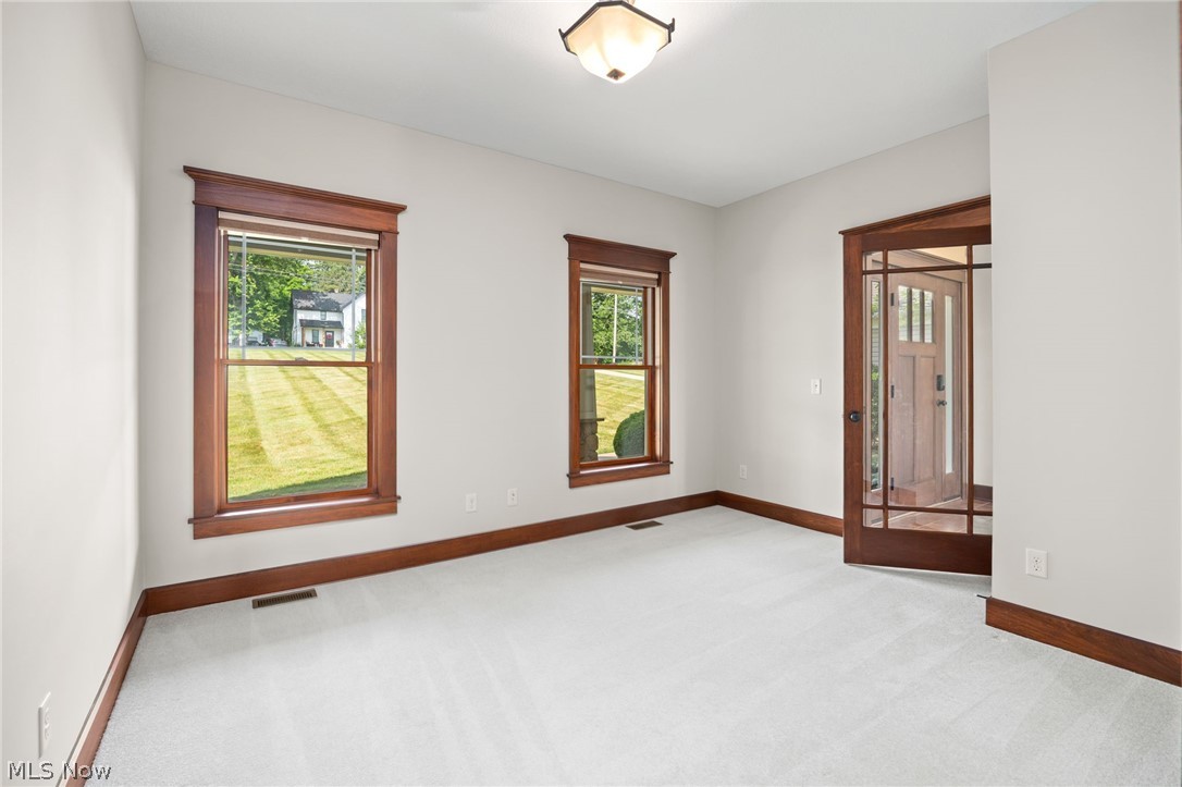 6925 River Styx Road Medina, OH 44256 - Photo 16 of 49 Room featuring two large windows with wood trim, light-colored carpet, and a wood-framed glass-paneled door