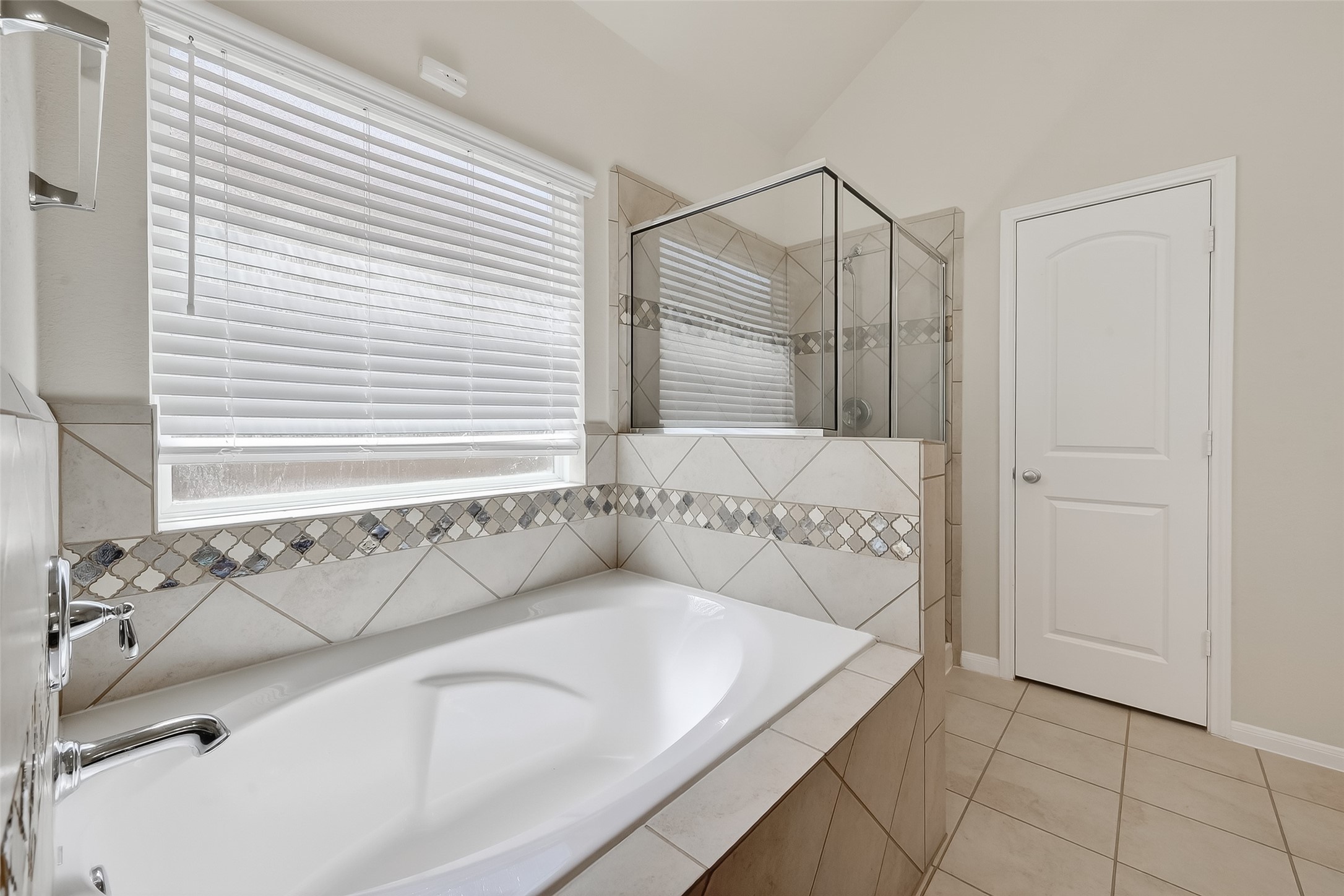 7631 Granite Terrace Lane Houston, TX 77083 - Photo 38 of 46 This bathroom features a spacious bathtub with elegant tile surround and a separate glass-enclosed shower, offering a modern and relaxing space.
