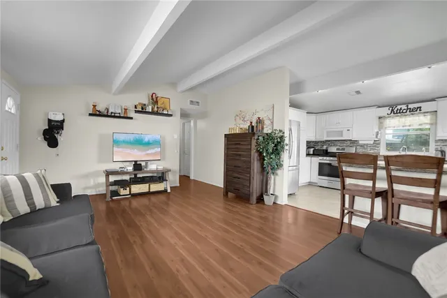 a living room with furniture and a flat screen tv with kitchen view