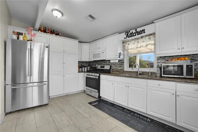 a kitchen with granite countertop a refrigerator sink and cabinets