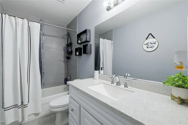 a bathroom with a granite countertop sink a toilet and shower