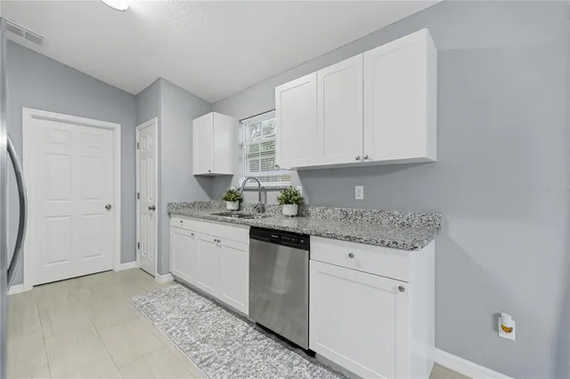 a kitchen with granite countertop white cabinets and white appliances