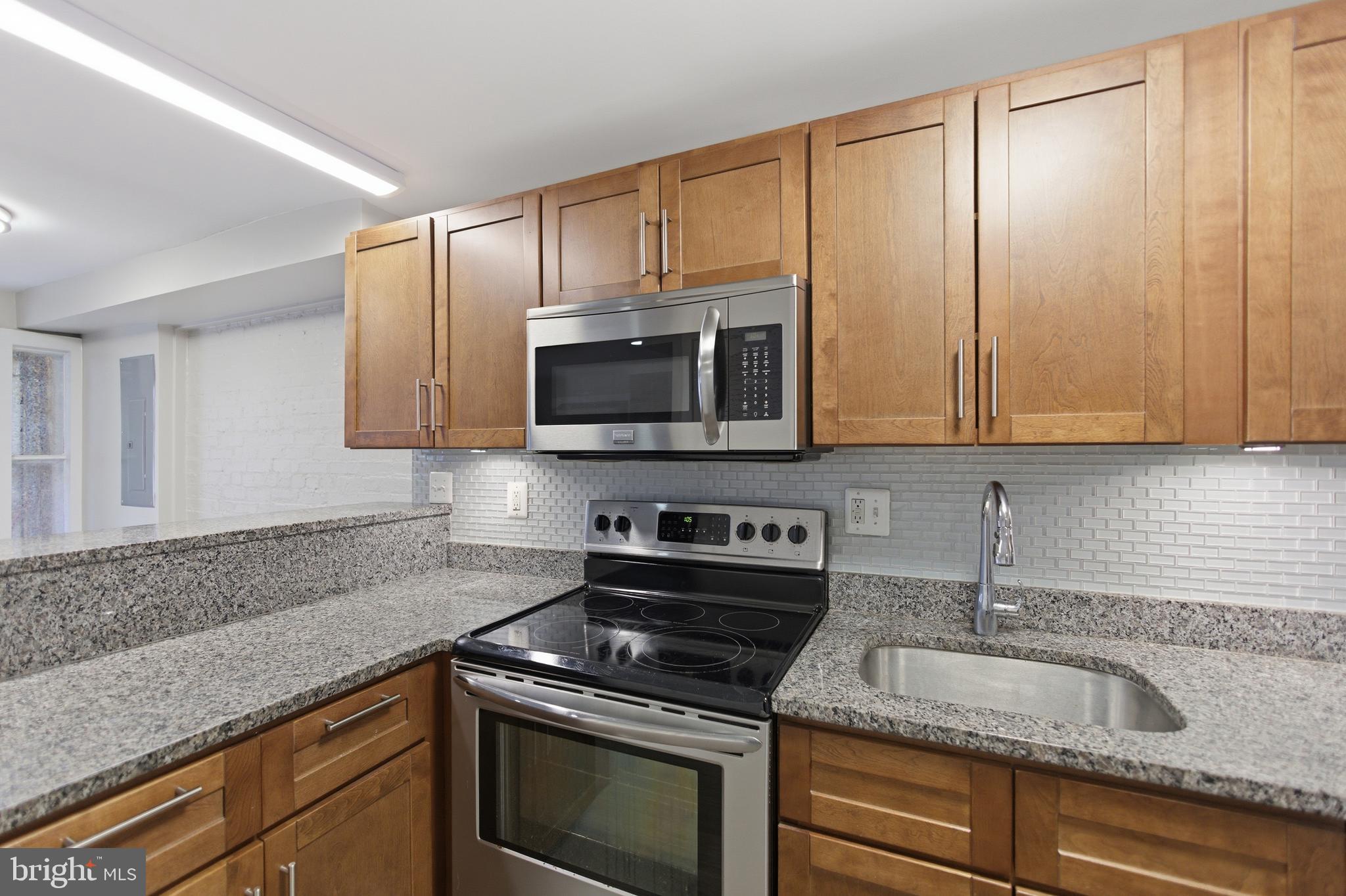 1451 Harvard Street Northwest, Unit 1 Washington, DC 20009 - Photo 11 of 24 a kitchen with granite countertop white cabinets and stainless steel appliances