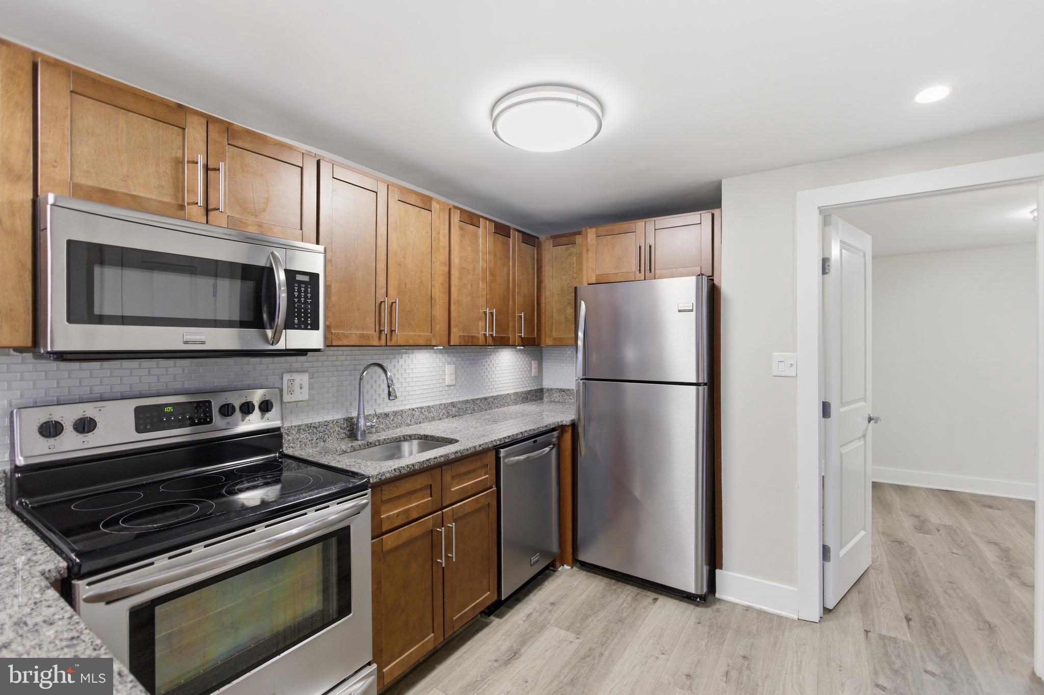 1451 Harvard Street Northwest, Unit 1 Washington, DC 20009 - Photo 13 of 24 a kitchen with stainless steel appliances granite countertop a stove microwave and refrigerator