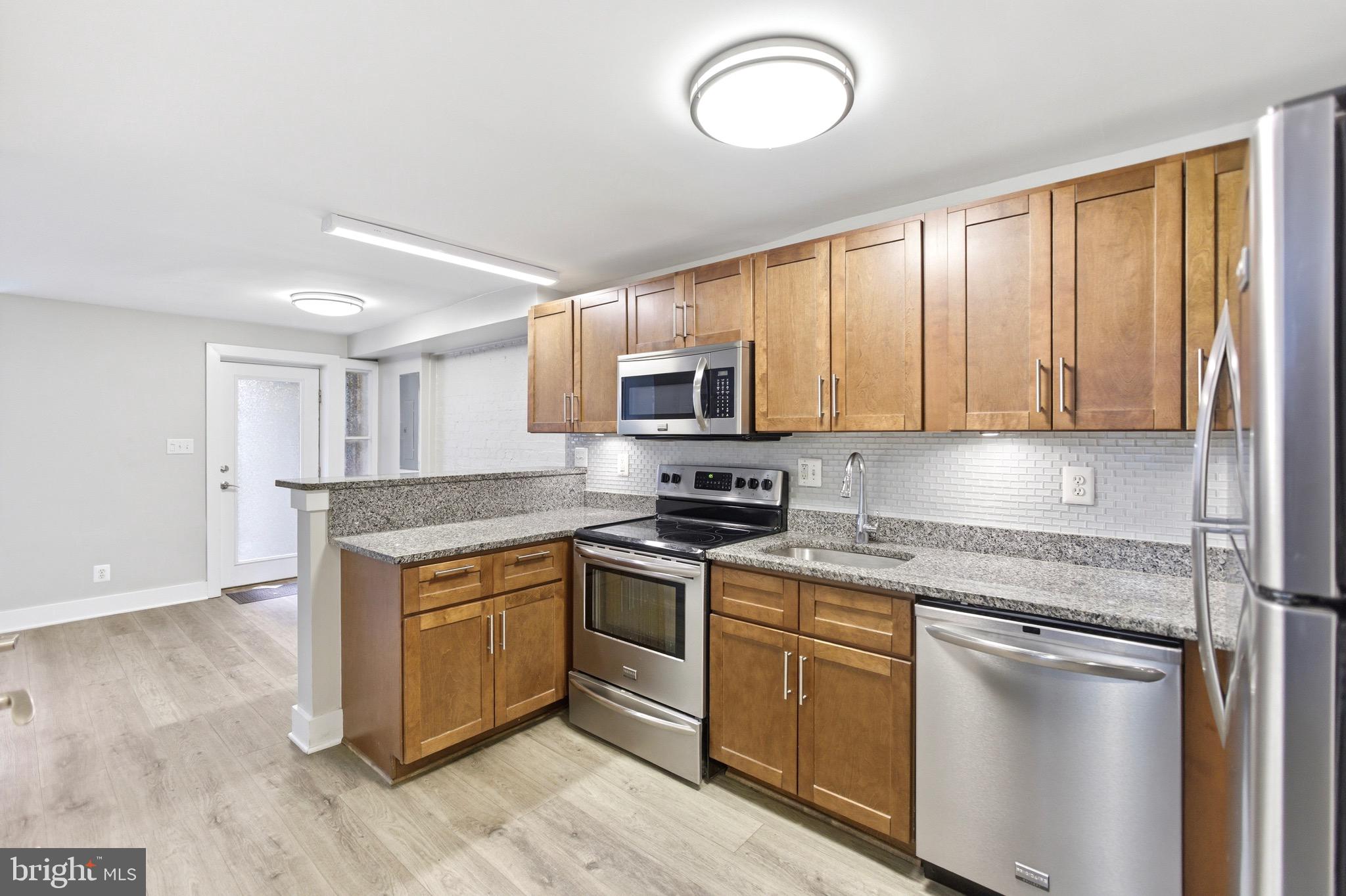 1451 Harvard Street Northwest, Unit 1 Washington, DC 20009 - Photo 6 of 24 a kitchen with stainless steel appliances granite countertop a stove a sink and a microwave