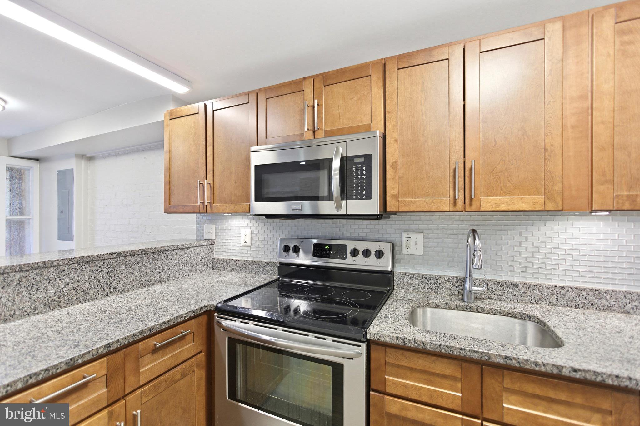 1451 Harvard Street Northwest, Unit 1 Washington, DC 20009 - Photo 10 of 24 a kitchen with granite countertop white cabinets and stainless steel appliances