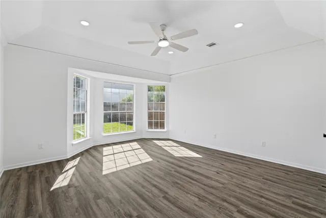 a view of an empty room with a window and wooden floor