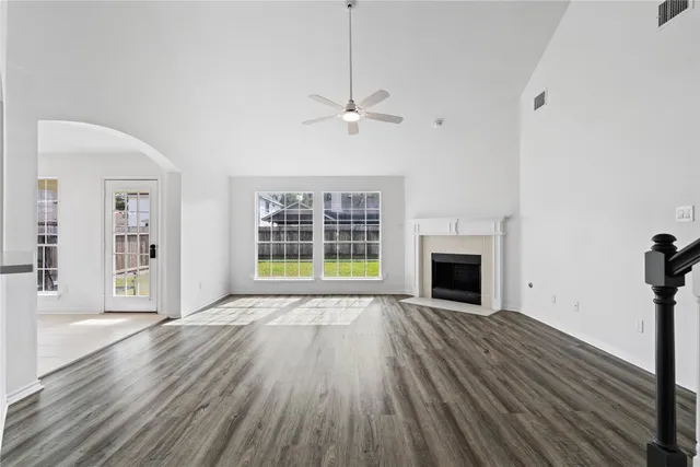 a view of an empty room with wooden floor fireplace and a window