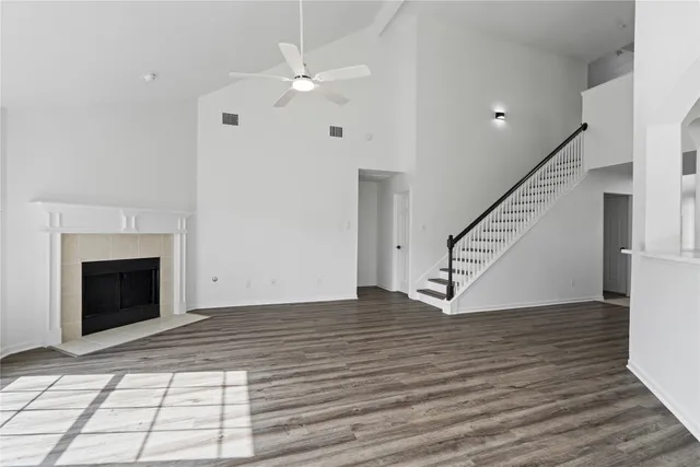 a view of an empty room with wooden floor fireplace and a window