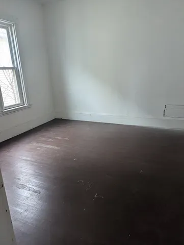 an empty room with wooden floor and windows with curtains