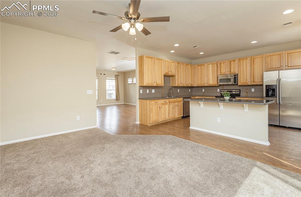 4815 Harrier Ridge Drive Colorado Springs, CO 80916 - Photo 28 of 33 Kitchen with stainless steel appliances, light wood finish cabinetry, open floor plan, dark countertops, and a kitchen island