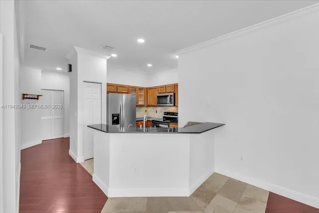 a view of a kitchen with stainless steel appliances wooden floor and a window