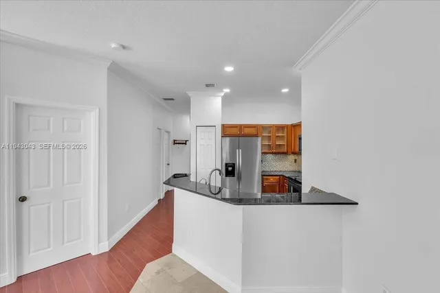 a living room with stainless steel appliances furniture a refrigerator and a kitchen view