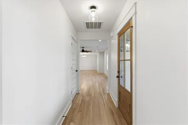 a view of a hallway with wooden floor and a bathroom