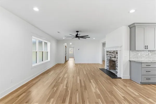 wooden floor in an empty room with a kitchen and a window