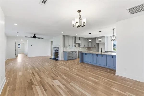 a view of kitchen and empty room with wooden floor