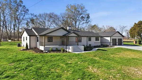a front view of a house with a yard patio and large tree
