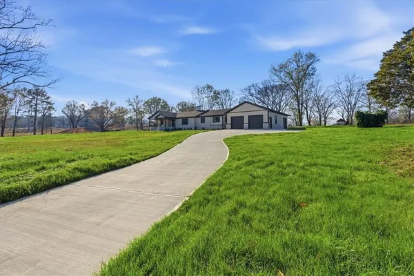 a view of a big house with a big yard and large trees