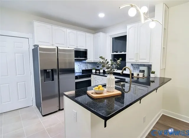 a kitchen with stainless steel appliances granite countertop a refrigerator a stove and a sink