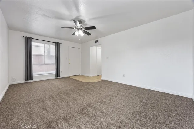 a view of an empty room and chandelier fan