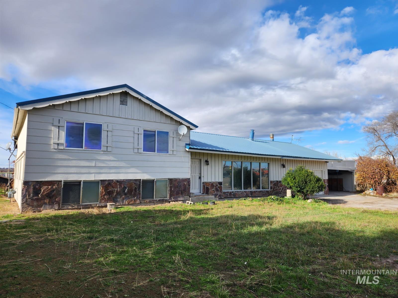 Tri-level home with an attached carport, a front lawn, board and batten siding, a metal roof, and concrete driveway