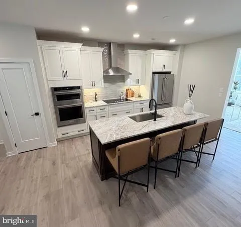 a kitchen with stainless steel appliances granite countertop a stove a refrigerator a sink a dining table and chairs with wooden floor