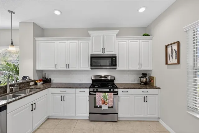 a kitchen with white cabinets a stove and microwave