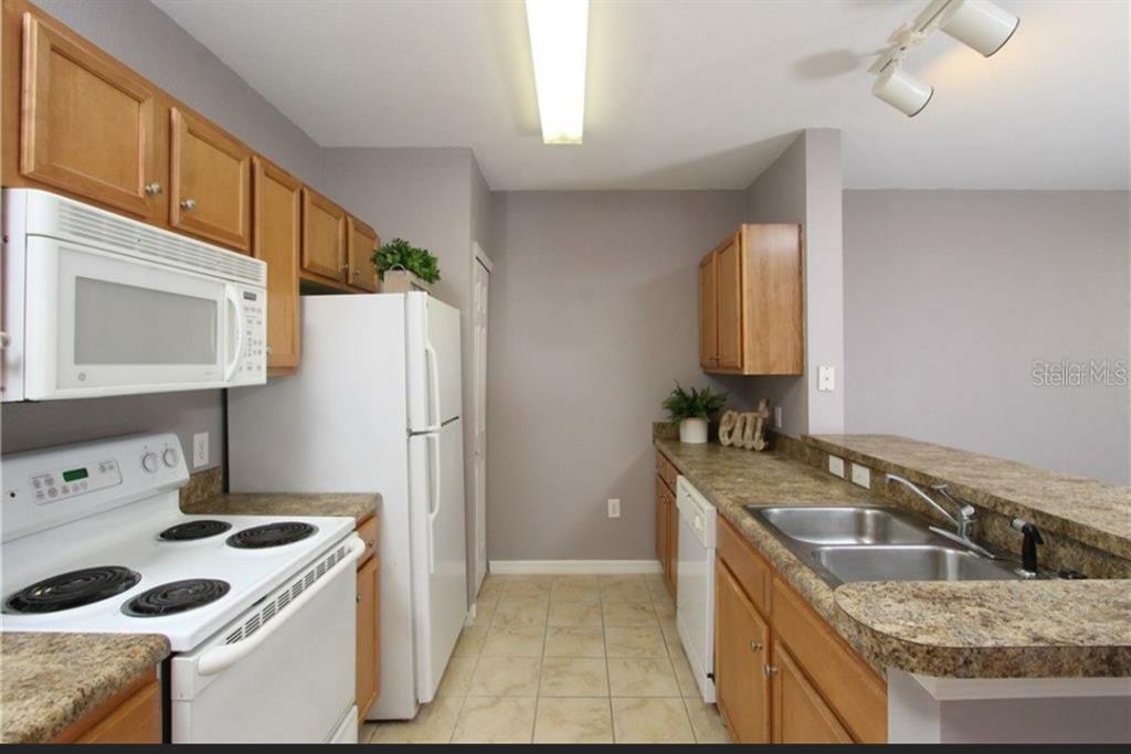5550 East Michigan Street, Unit 3120 Orlando, FL 32822 - Photo 7 of 17 a kitchen that has a sink a stove and a refrigerator