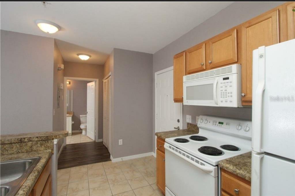 5550 East Michigan Street, Unit 3120 Orlando, FL 32822 - Photo 8 of 17 a kitchen with a stove a refrigerator and a sink