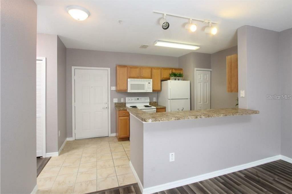 5550 East Michigan Street, Unit 3120 Orlando, FL 32822 - Photo 9 of 17 a view of a kitchen with a sink and dishwasher a refrigerator with wooden floor