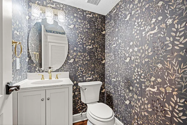 a open kitchen with stainless steel appliances granite countertop a refrigerator a stove oven and white cabinets with wooden floor