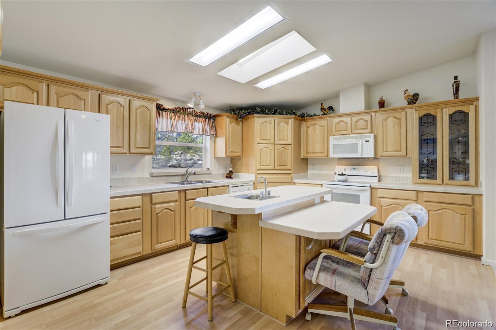 688 Tiara Road Lake George, CO 80827 - Photo 8 of 46 a kitchen with a refrigerator a stove a sink and white cabinets with wooden floor