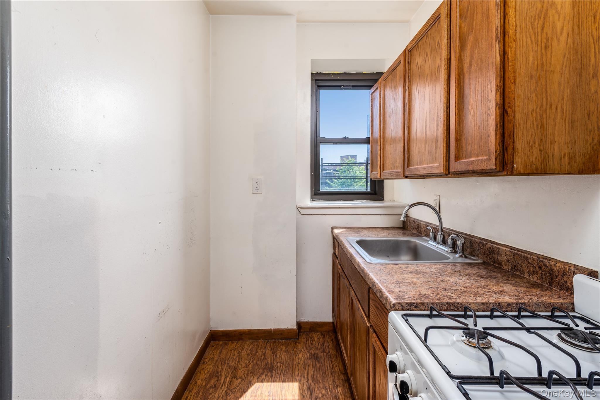 95 South 10th Street, Unit 22 Brooklyn, NY 11249 - Photo 5 of 8 Kitchen featuring white gas stove, brown cabinetry, dark wood finished floors, and dark countertops