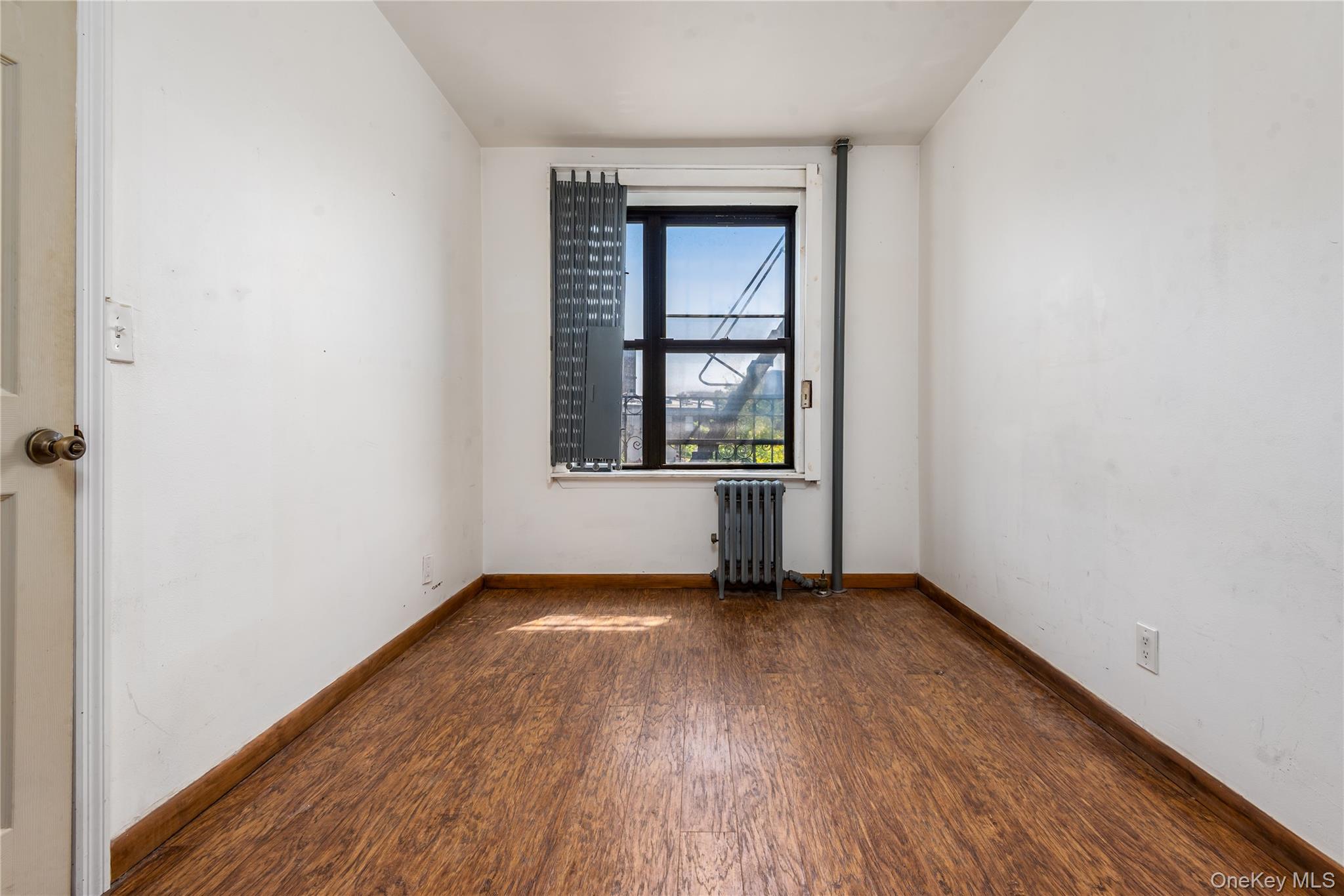 95 South 10th Street, Unit 22 Brooklyn, NY 11249 - Photo 8 of 8 Unfurnished room featuring dark wood-style floors and radiator heating unit