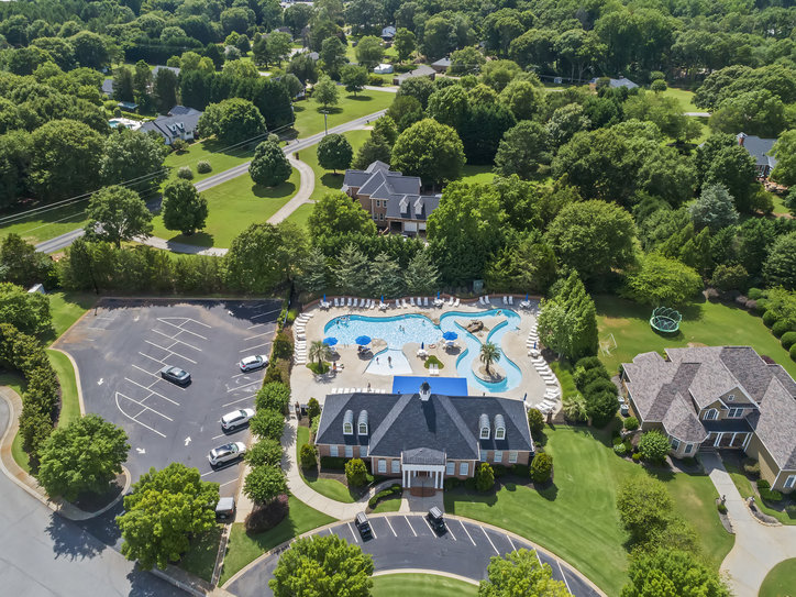 121 Loudwater Drive Anderson, SC 29621 - Photo 3 of 3 An aerial view captures a spacious pool area next to a grand clubhouse, surrounded by verdant trees.