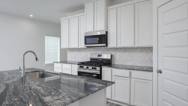 a kitchen with granite countertop a stove a sink and a microwave