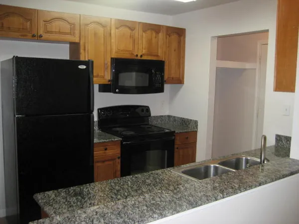 a kitchen with a granite countertop sink and cabinets