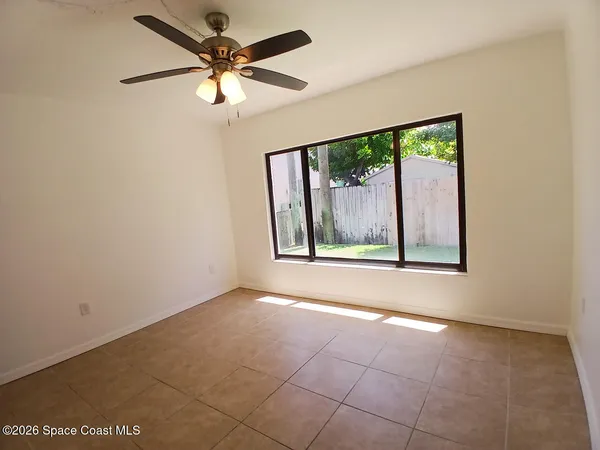 an empty room with windows and fan
