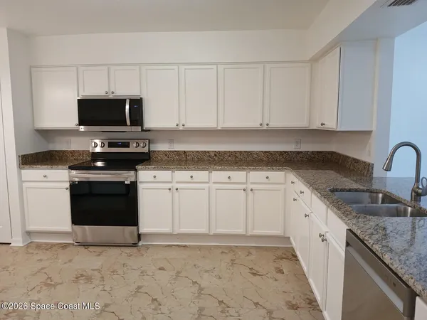 a kitchen with granite countertop a sink a stove and cabinets