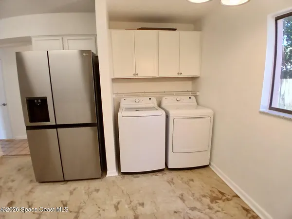 a view of kitchen with refrigerator and white cabinets