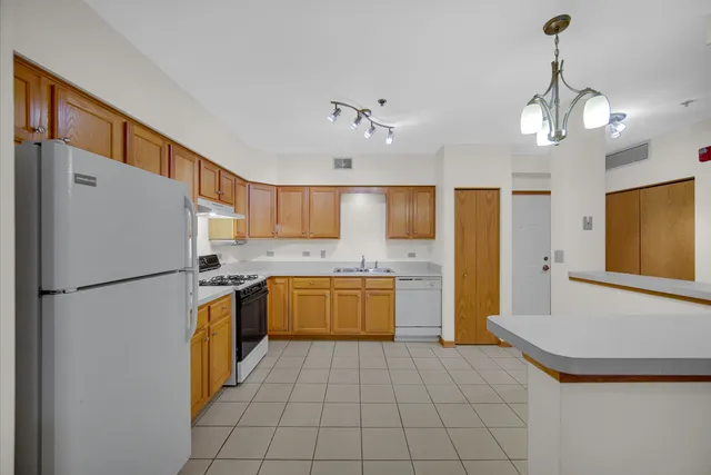 a kitchen with a refrigerator a stove top oven a sink dishwasher and a refrigerator with wooden floor