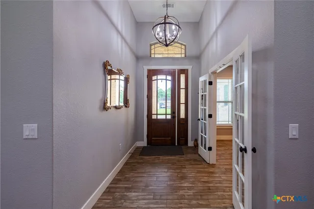 a view of a hallway with wooden floor and a chandelier