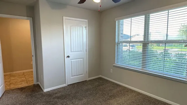 an empty room with windows and fan