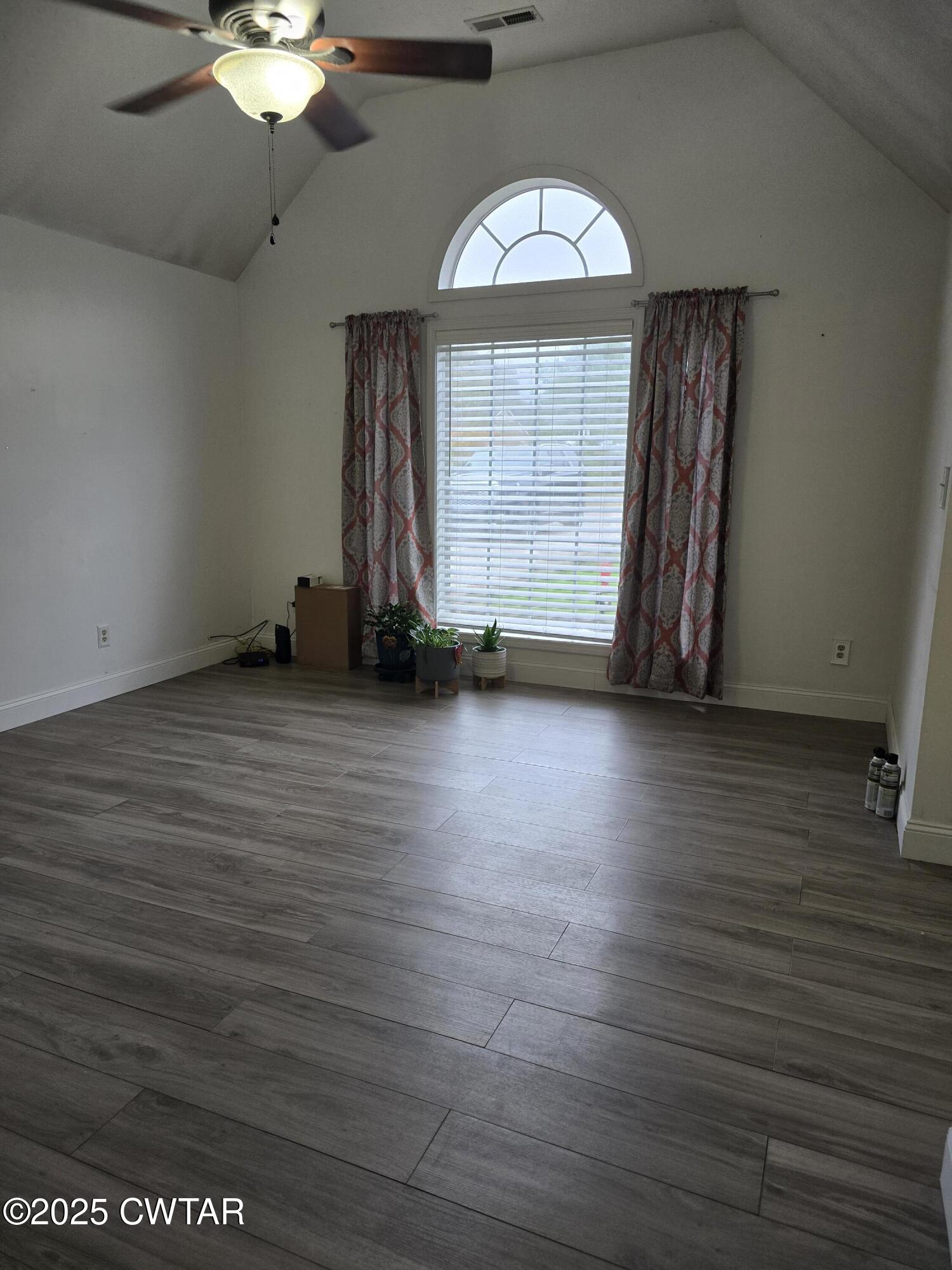143 Elizabeth Cove Selmer, TN 38375 - Photo 5 of 14 an empty room with wooden floor chandelier fan and windows