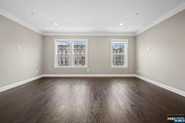 a view of an empty room with wooden floor and window