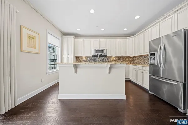 a kitchen with stainless steel appliances granite countertop a refrigerator a stove a sink and a microwave