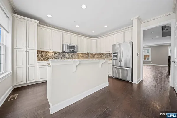 a kitchen with stainless steel appliances granite countertop a refrigerator sink and white cabinets
