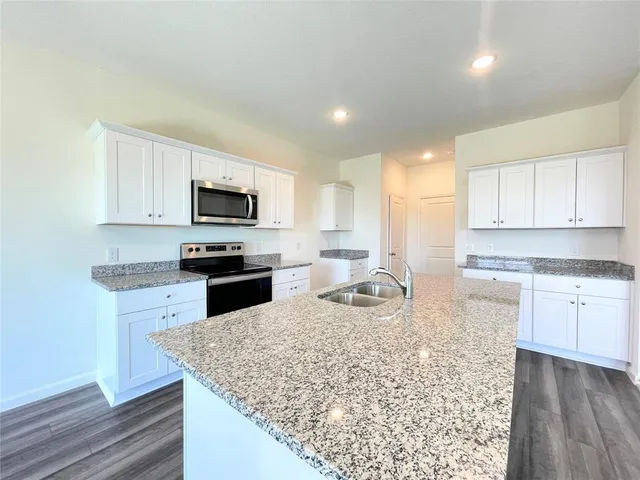 a kitchen with stainless steel appliances kitchen island sink refrigerator and cabinets