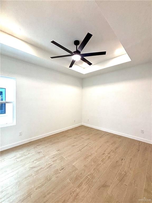 4 Estevan Street Mission, TX 78573 - Photo 6 of 24 Room featuring a black ceiling fan with integrated lighting, a tray ceiling, recessed lighting, wood-finish flooring, and white baseboards
